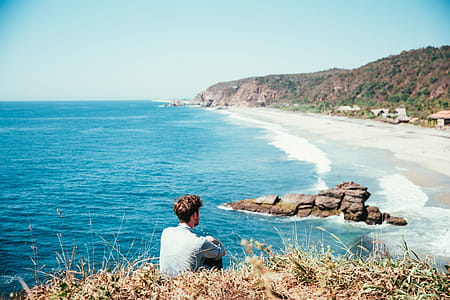A young caucasian man sitting alone watching the beach from the top thumbnail