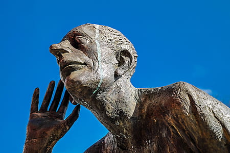 worm's-view photo of man listening statue thumbnail