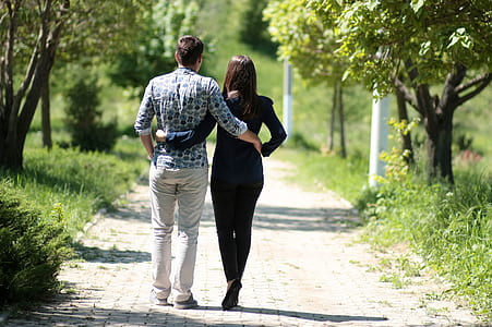 couple holding each others waist while walking on pathway during daytime thumbnail