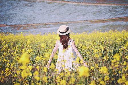 woman wearing white sleeveless top standing on field of flowers during daytime thumbnail