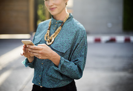 woman in teal dress shirt holding her gold iPhone 6 thumbnail