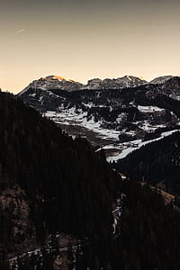 aerial view photography of green forest near high-rise mountain under white sky thumbnail
