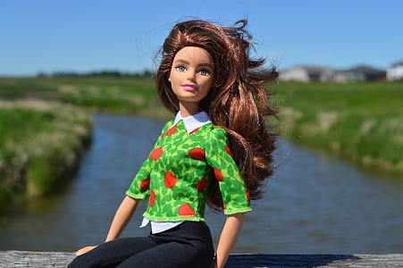 barbie doll on gray platform near river during daytime thumbnail