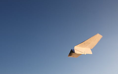 tilt-shift lens photography of white paper plane in flight during daytime thumbnail