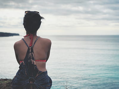 woman in red and black bikini sitting at seaside during daytime thumbnail