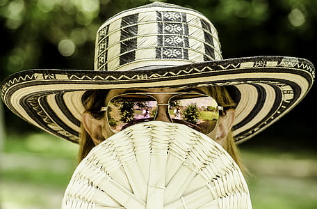 selective focus photo of woman holding brown wicker hand fan thumbnail