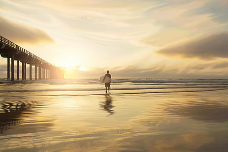 man carrying surfboard on beach side thumbnail