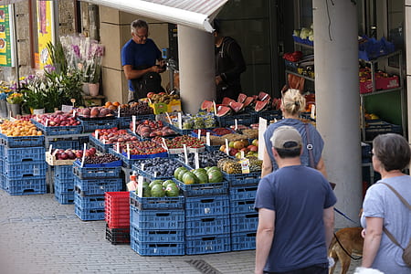 several people standing in front of variety of fruits on blue crates thumbnail