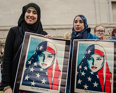 two women holding woman portrait during daytime thumbnail