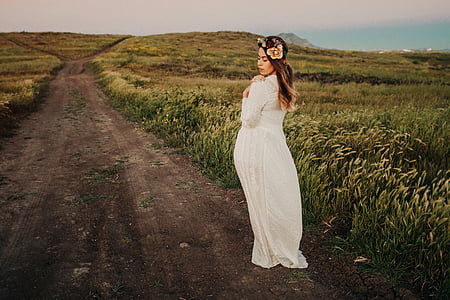 woman walking near tall grass field during daytime thumbnail