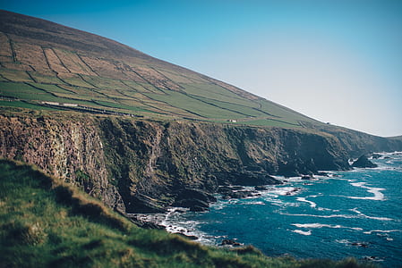 green and brown mountain cliff beside of the ocean photography thumbnail
