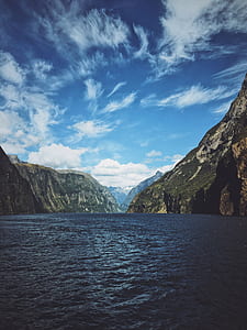 body of water between mountains during daytime thumbnail