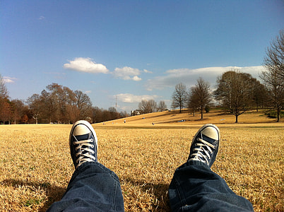 photo of person in black pants and Converse All Star shoes laying on grass thumbnail