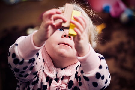 baby's holding brown and yellow brick toy thumbnail