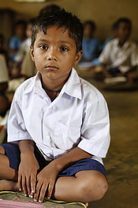 boy wearing school uniform sitting on the ground thumbnail