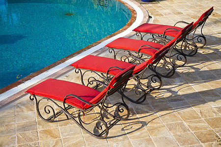 four red-and-black metal loungers near pool thumbnail