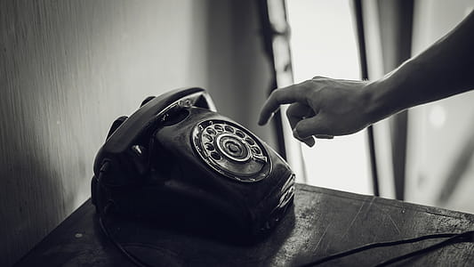 Grayscale Photo of Rotary Telephone Beside Person Hand thumbnail