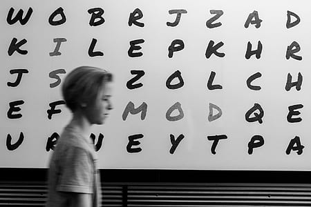 grayscale photo of boy beside on alphabet wall thumbnail