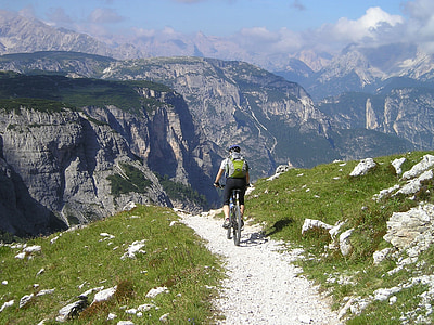 man riding on bicycle near mountain range thumbnail