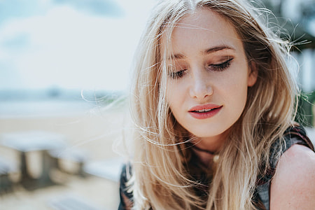 Beautiful blonde woman relaxing with a can of coke on a tree stump by the beach thumbnail