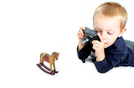 boy taking a picture of rocking horse toy thumbnail