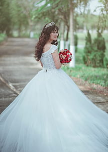 Woman in White Wedding Dress Holding Red Bouquet thumbnail
