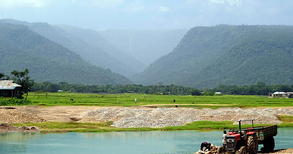 tractor on field near water during daytime thumbnail