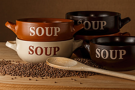 assorted color Soup bowls with brown wooden spoon on beige wooden table thumbnail