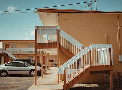 brown and white 2-storey building with parked cars thumbnail