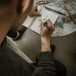 man drawing on notepad in closeup photography thumbnail