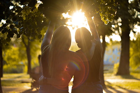 two women standing while reaching tree during daytime thumbnail