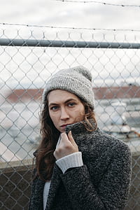 woman holding coat collar near chain link fence thumbnail