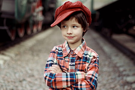 standing boy in plaid long-sleeved shirt with red newsboy hat thumbnail