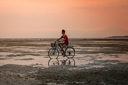 man riding bicycle on wet land thumbnail