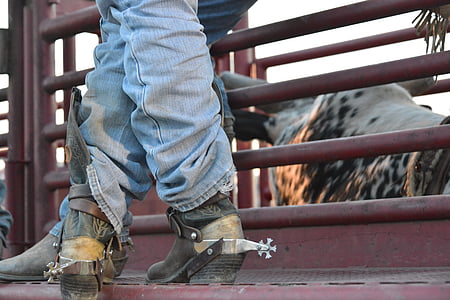 person wearing blue jeans and cowboy boots near animal cage thumbnail