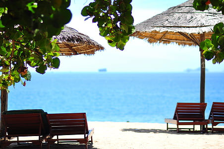 selective focus photograph of two lounger under tiki umbrella thumbnail