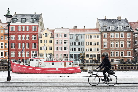 man riding bicycle near red and white boat at daytime thumbnail