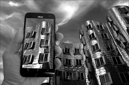 person holding Asus ZenFone displaying highrise buidling thumbnail