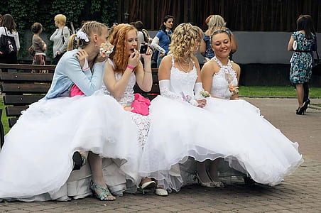 four women in dresses sitting on bench thumbnail
