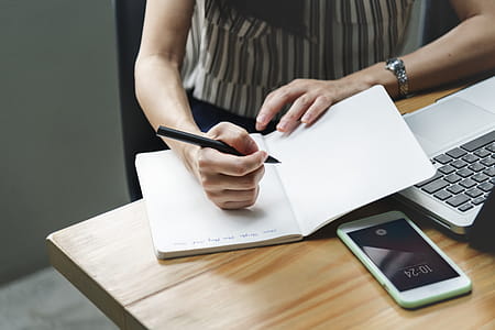 Woman Holding Pen Beside Laptop thumbnail