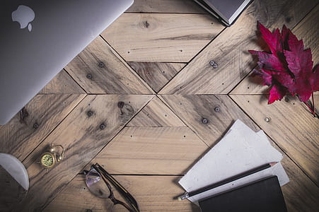 eyeglasses, printer paper, and MacBook Pro on brown wooden surface thumbnail