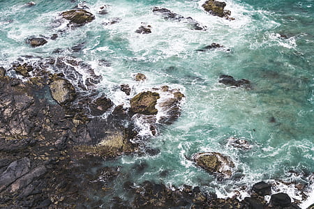 teal body of water beside rock formation thumbnail