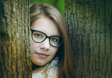 woman wearing crocheted white shirt and black framed eyeglasses standing between trees thumbnail