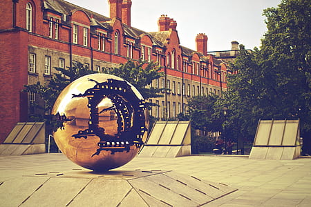 round gold monument near trees and concrete building thumbnail