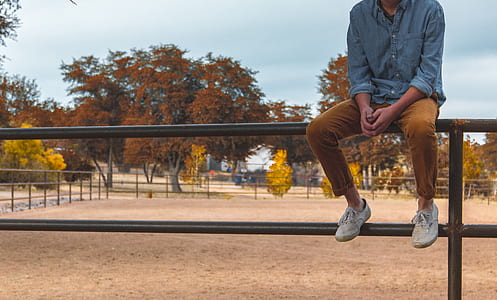 person sitting on handrail during daytime thumbnail