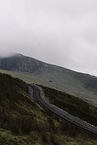 aerial photo of train rail near gray and green mountain range under cloudy sky during daytime thumbnail