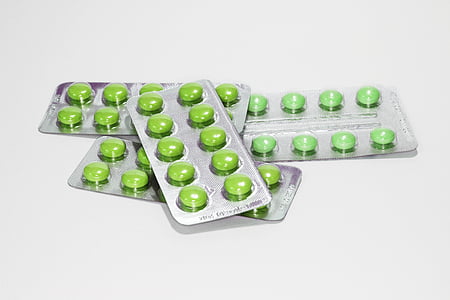 four green pill blisters on white surface thumbnail