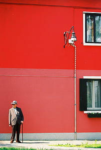 man in suit standing near wall with lamp post thumbnail