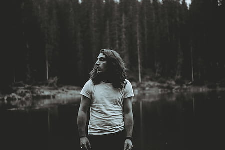 grey scale photography of man standing near river thumbnail