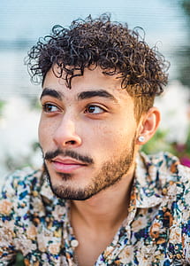 man wearing blue, white, and orange floral top thumbnail